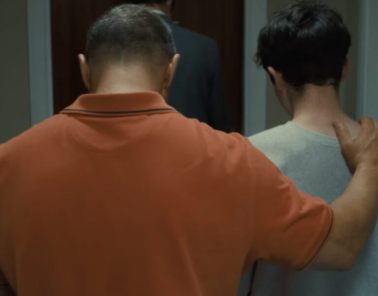 A man and son walk down a corridor together