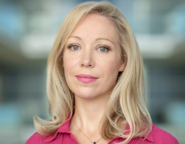 A woman in a pink shirt looking into camera