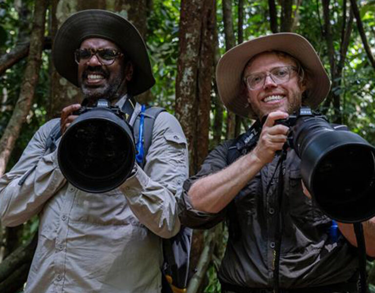 Two men holding cameras with large lenses