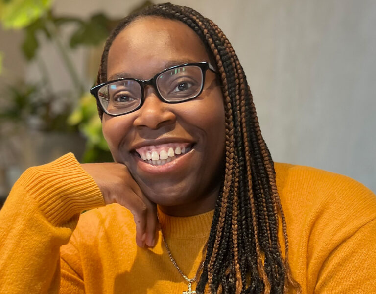 A woman in orange smiling into camera