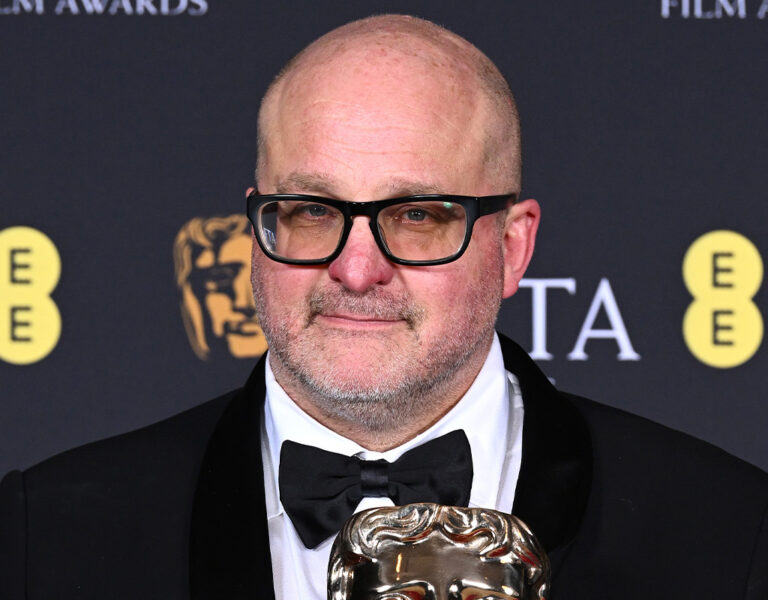 Michael Bauman holding a trophy in a tuxedo