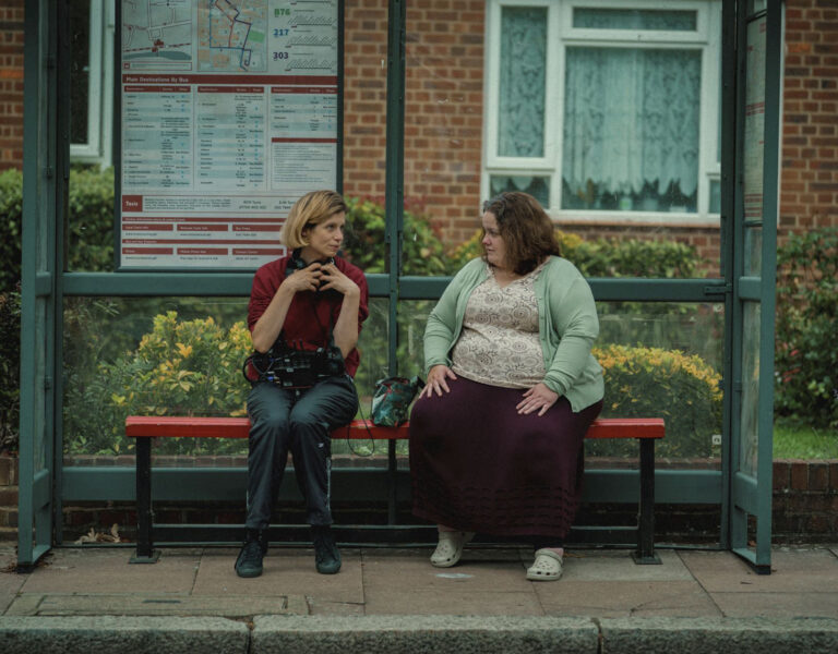 Two people talking at a bus stop