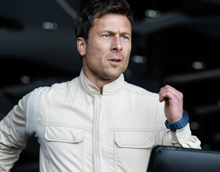 Glen Powell in a white outfit running