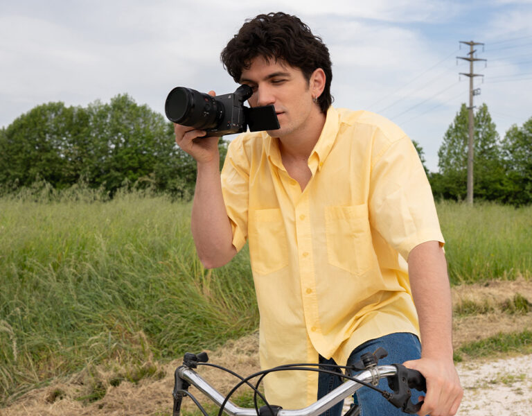 A man on a bike looking through a camera