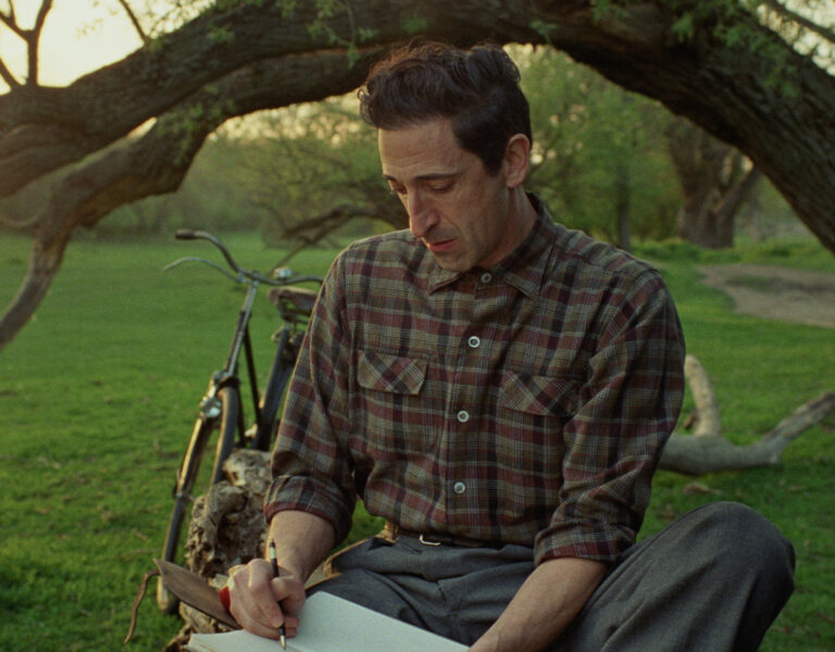 Adrien Brody writing under a tree